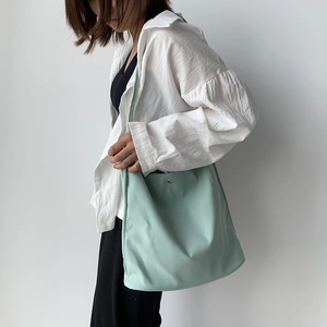 Mint green nylon tote bag on a model showing large capacity and fresh minimalist style