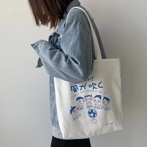 Detail of off-white canvas tote with blue cartoon illustration and fabric handle