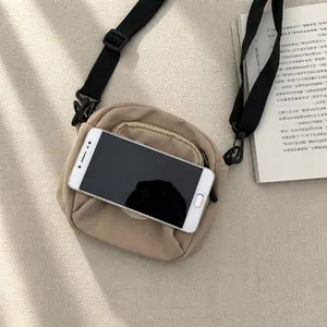 Macro shot of a khaki nylon crossbody bag showing the storage capacity for a smartphone