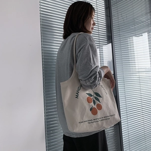 Sac fourre-tout en toile minimaliste avec imprimé orange porté par un mannequin