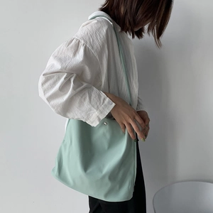 Close-up of mint green nylon shoulder bag showing soft texture and metal magnetic buckle