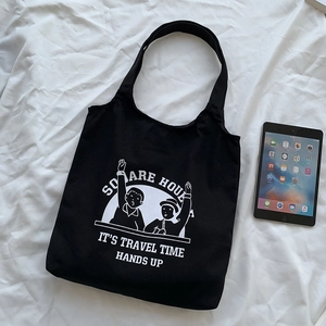 Close-up of black canvas tote bag featuring white cartoon illustration and text design