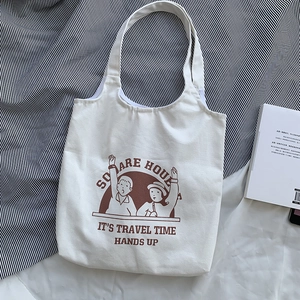 Close-up of white canvas tote with vintage brown cartoon print and square house text