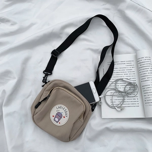 Detalle de bolso bandolera de lona beige con correa ajustable y accesorios de estilo vida