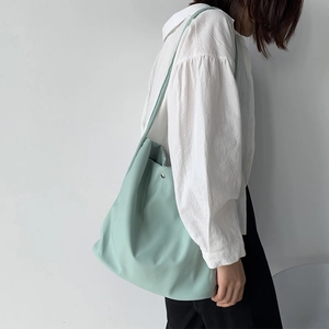 Detail of mint green minimalist nylon tote bag featuring soft folds and silver button