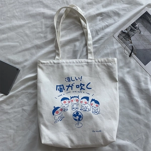 Detail of white canvas tote bag featuring blue Japanese cartoon print and sturdy fabric texture