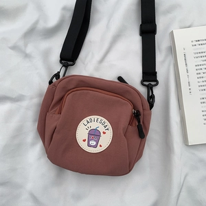 Detalle del bolso bandolera de lona rosa vintage con correa ajustable sobre un libro