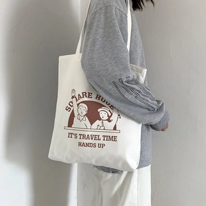 Close-up of white canvas tote bag with brown vintage illustration and long shoulder straps