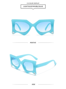 Close-up of light blue geometric sunglasses with wavy frames and heart diamond accents