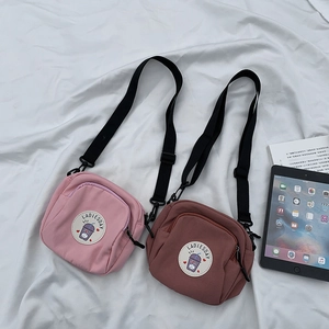 Detalle de bolsos bandolera pequeños de lona en rosa y marrón con doble cremallera