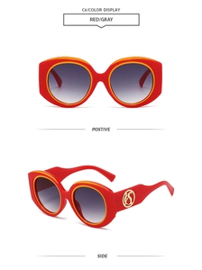 Detail of red and yellow sun glasses with golden S-logo and gray gradient lenses