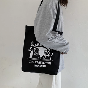 Detailed side view of a black canvas tote bag featuring white cartoon character print