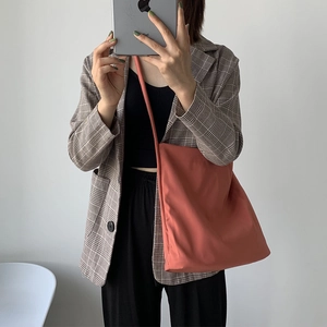Detailed shot of a minimalist brick red nylon crossbody tote bag with soft texture