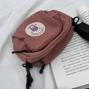 Detalle de bolso bandolera de lona rojo ladrillo con bordado de Ladiesday y cremalleras