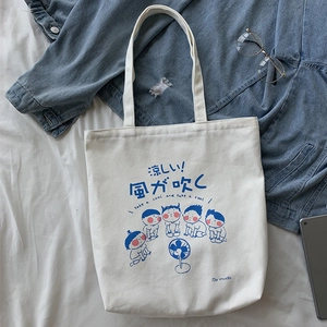 Detail view of canvas tote bag with Japanese cartoon print and casual accessories