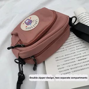Detail of dusty rose crossbody bag featuring double zippers and round cartoon patch