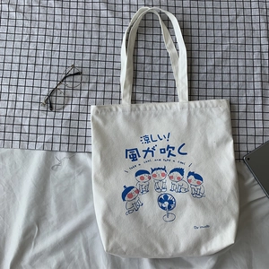 Flat lay of Japanese cartoon canvas tote bag with glasses and tablet on bedding