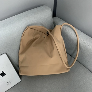 Close-up of khaki nylon tote bag with magnetic snap closure on a grey fabric sofa
