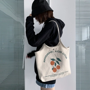 Détail du sac cabas en toile crème montrant l'imprimé orange et le bouton pression