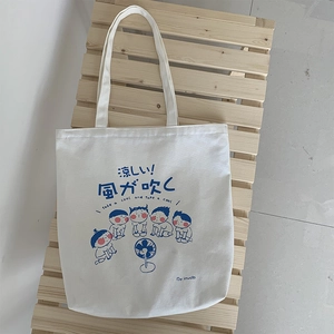Detail of a Japanese cartoon canvas tote bag placed on a minimalist wooden stand