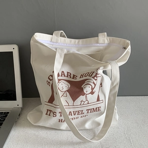 Close-up of white canvas tote bag with cartoon illustration and secure top zipper closure