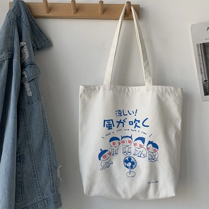 Detail of off-white canvas tote bag featuring blue Japanese-style cartoon illustrations