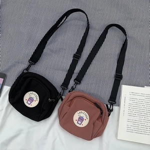 Detalle de mini bolsos bandolera de lona con parches florales y correas ajustables