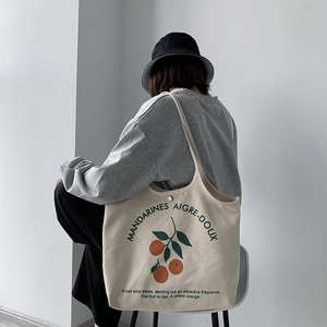 Détail du sac cabas en toile avec imprimés d'oranges et bouton pression en métal chic