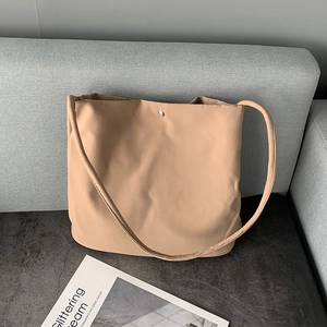 Detail view of a beige nylon tote bag featuring a silver metal snap button closure