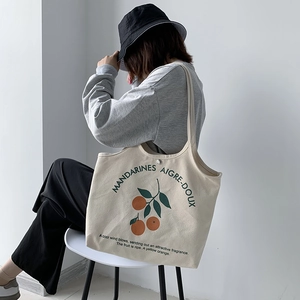 Détail du sac cabas en toile avec motif orange et boucle magnétique sur le modèle