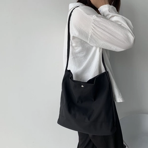 Close-up of minimalist black canvas tote bag with metal snap button closure detail