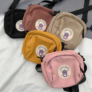 Detalle de mini bolsos bandolera de lona en cinco colores con bordado circular frontal