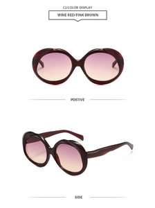 Detail view of oval wine red sunglasses with purple gradient lenses and wavy frame texture