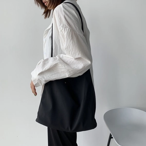 Model wearing a minimalist large capacity black nylon canvas tote bag for daily commute