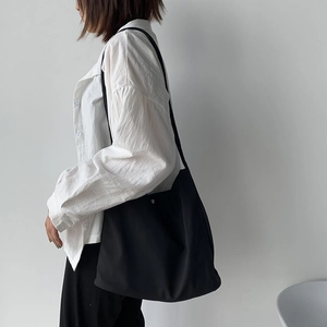 Minimalist black nylon tote bag shown on shoulder for daily commute and style