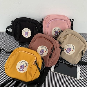 Bolso bandolera de nailon en varios colores con teléfono para comparar el tamaño