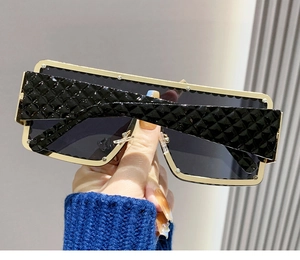 Detail view of large gold metal frame sunglasses featuring black textured temples