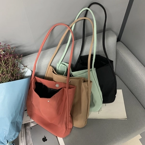 Detail of four colorful nylon tote bags with magnetic snaps on a minimalist sofa