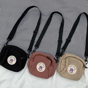 Tres bolsos bandolera minimalistas de lona en negro, rosa y beige con correa ajustable