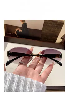Close-up of rimless oval sunglasses with purple gradient lenses and gold metal accents