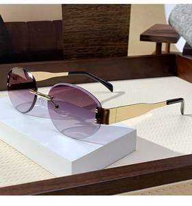 Close-up of rimless oval sunglasses with purple gradient lenses and gold metal temples