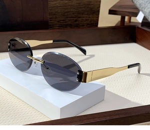 Detail of rimless sunglasses with blue oval lenses and gold metal temples on a display