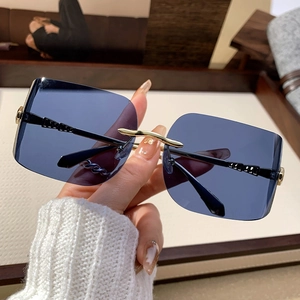 Handheld view of rimless square sunglasses with blue gradient lenses and gold metal details