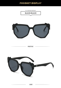 Detail view of black oversized geometric sunglasses with silver wing temple accents