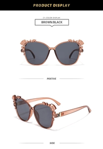 Detail of oversized butterfly sunglasses with rhinestone floral accents and brown frames