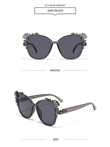 Detail of oversized grey sunglasses with rhinestone bow accents and dark tinted lenses