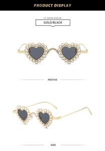 Detail view of heart-shaped sunglasses with gold rhinestone-studded frame and black lenses