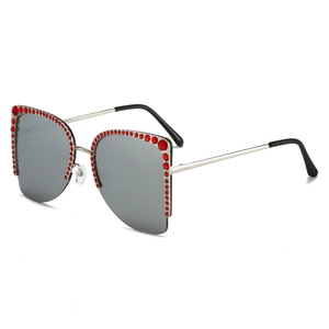 Cat-Eye Sonnenbrille mit silbernem Rahmen und roten Strasssteinen auf weißem Hintergrund