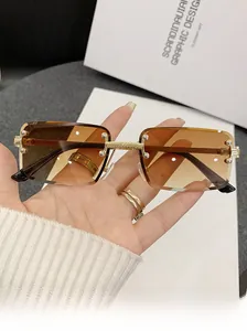 Detail of square rimless sunglasses with gradient brown lenses and gold metal accents