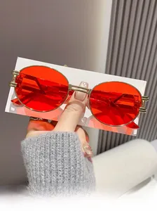 Detail view of oval red lenses and gold metal frame on retro fashion sunglasses